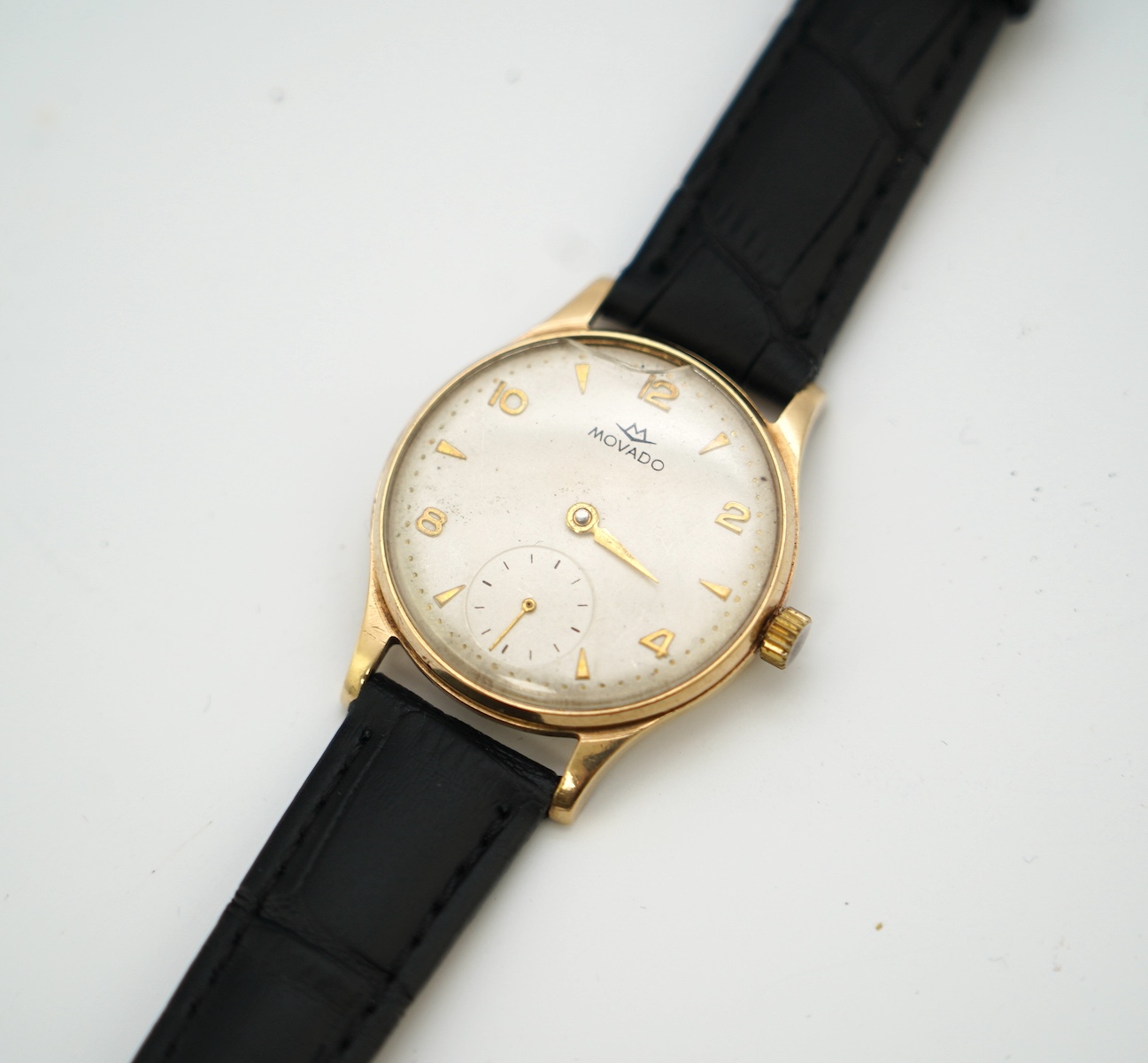 A gentleman's 9ct gold Movado manual wind wrist watch, with baton and Arabic numerals, on associated leather strap, case diameter 32mm. Condition - poor